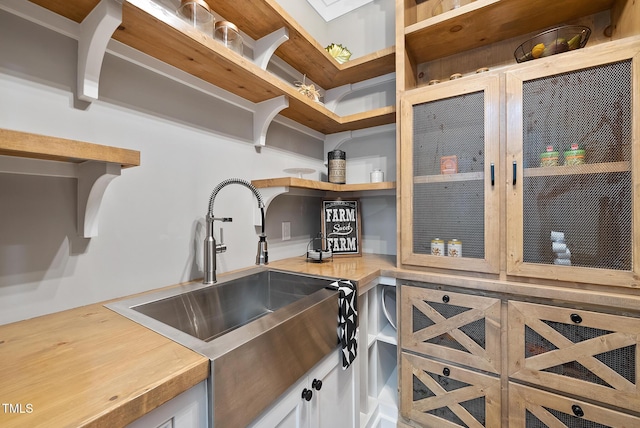 kitchen featuring white cabinetry, open shelves, wooden counters, and a sink