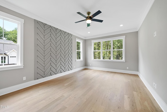 spare room with crown molding, light wood-style flooring, baseboards, and a wealth of natural light