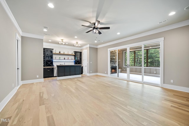 unfurnished living room with baseboards, visible vents, ornamental molding, a lit fireplace, and light wood-style floors