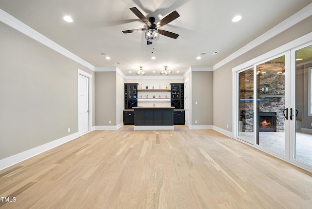 unfurnished living room with indoor wet bar, a fireplace, light wood-type flooring, and ornamental molding