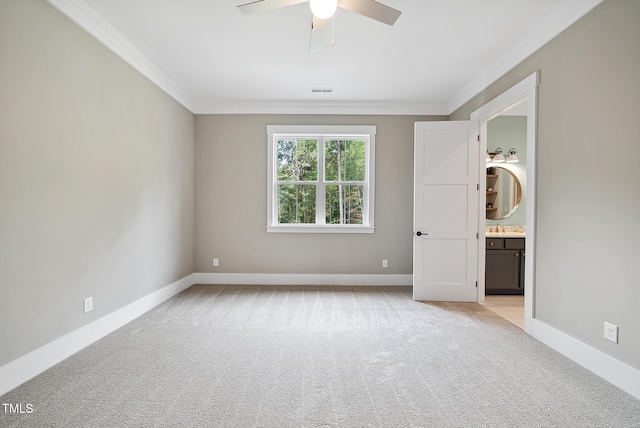 empty room with light carpet, crown molding, and baseboards