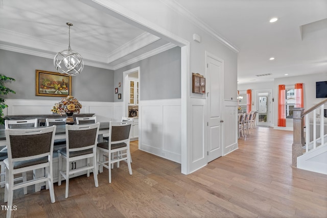 dining space with recessed lighting, stairs, light wood-style floors, wainscoting, and a notable chandelier