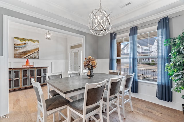 dining room with light wood-style floors, a notable chandelier, visible vents, and crown molding