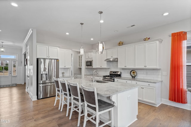 kitchen featuring light wood-style flooring, a sink, under cabinet range hood, appliances with stainless steel finishes, and white cabinets