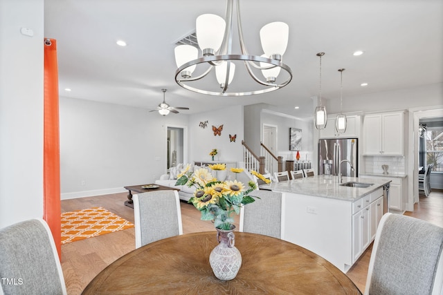 dining room featuring recessed lighting, light wood-type flooring, baseboards, and ceiling fan with notable chandelier