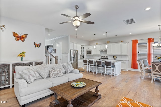 living area featuring light wood finished floors, visible vents, ceiling fan with notable chandelier, and recessed lighting