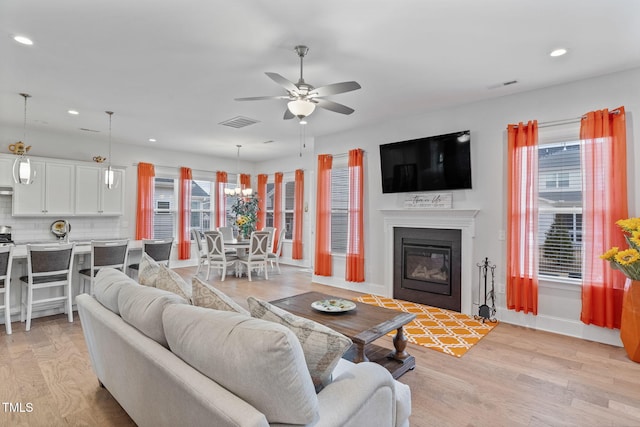 living room featuring visible vents, recessed lighting, light wood-type flooring, and a glass covered fireplace