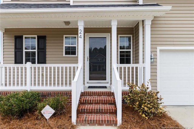 property entrance with a garage, covered porch, and roof with shingles