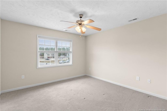 carpeted empty room featuring a textured ceiling, ceiling fan, visible vents, and baseboards