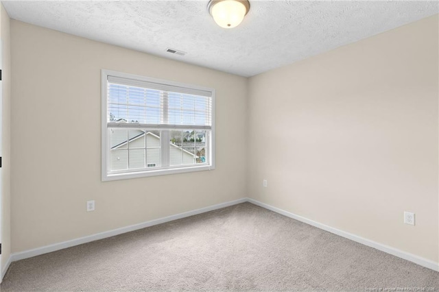 carpeted spare room with a textured ceiling, visible vents, and baseboards