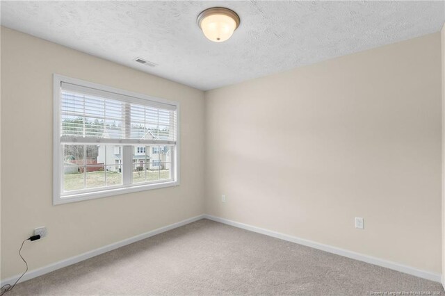 unfurnished room with visible vents, a textured ceiling, baseboards, and carpet flooring