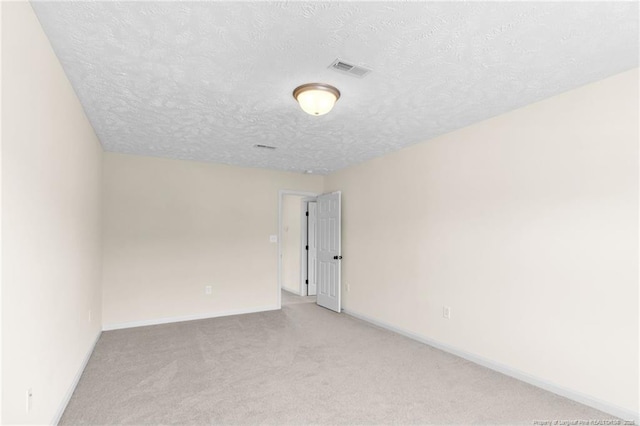 empty room featuring visible vents, baseboards, a textured ceiling, and light colored carpet