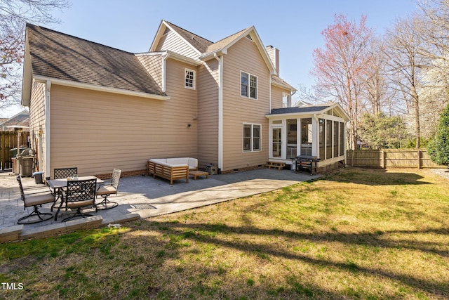 rear view of house featuring a patio area, a chimney, a yard, and a sunroom