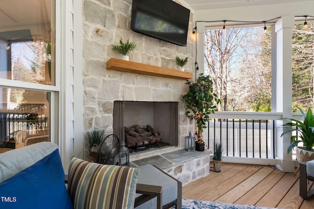 living area with a stone fireplace and wood finished floors