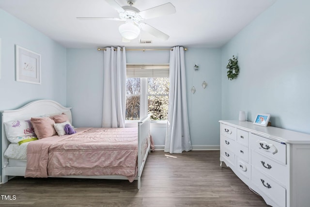 bedroom with a ceiling fan, wood finished floors, visible vents, and baseboards