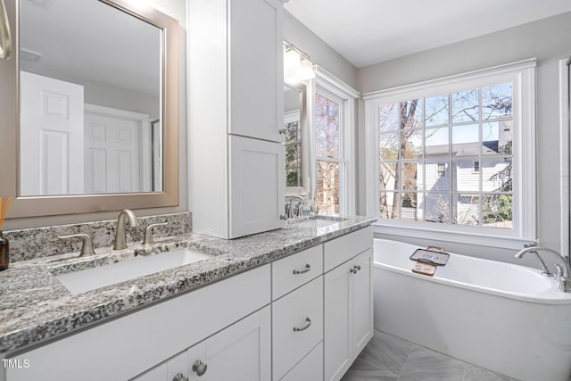 bathroom with a sink, a freestanding bath, and double vanity