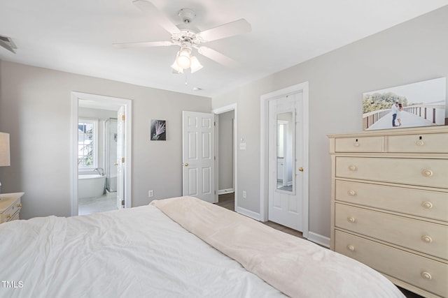 bedroom with ceiling fan, ensuite bath, and baseboards