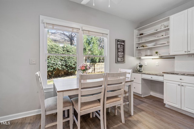 dining room featuring baseboards, light wood-style floors, a ceiling fan, and built in study area