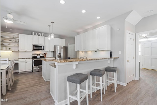 kitchen with stainless steel appliances, a peninsula, decorative backsplash, and white cabinetry