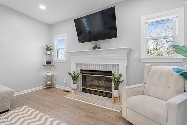 living room with wood finished floors, baseboards, visible vents, recessed lighting, and a fireplace