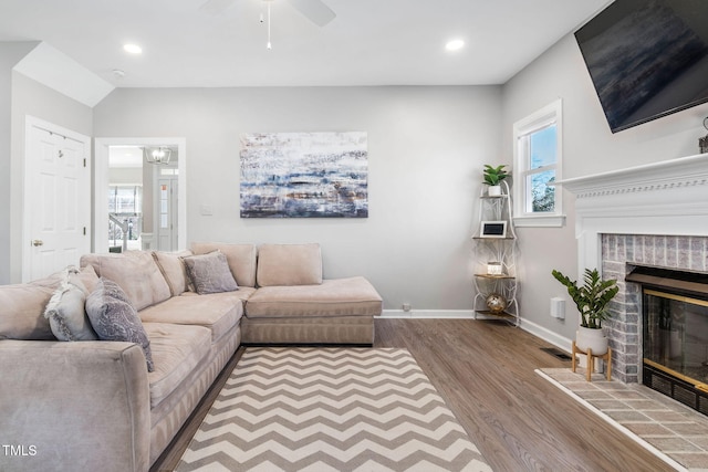 living room featuring a glass covered fireplace, recessed lighting, wood finished floors, and baseboards