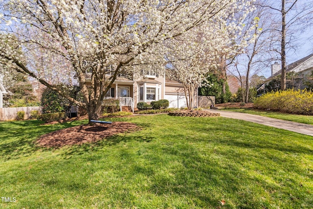 view of property hidden behind natural elements featuring a garage, concrete driveway, a front lawn, and fence