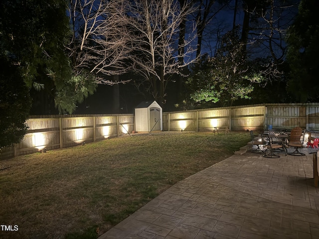 yard at twilight featuring a patio, an outdoor structure, a fenced backyard, and a shed