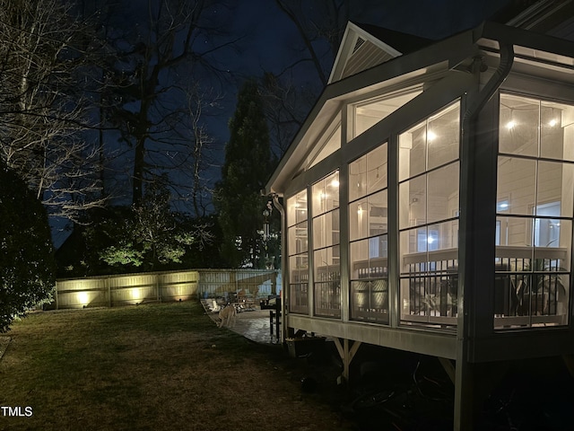 property exterior at night featuring a lawn