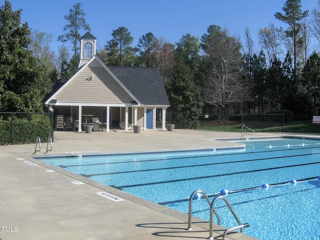 pool with a patio, a storage structure, fence, and an outbuilding