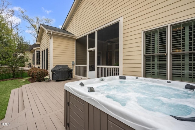 wooden deck with grilling area, a hot tub, fence, and a sunroom