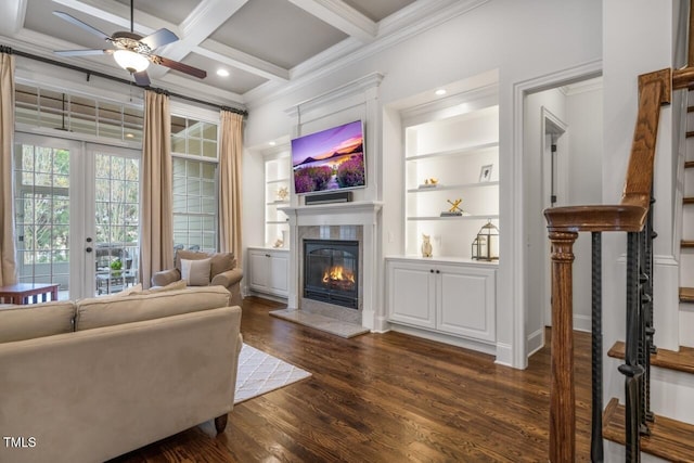 living room featuring coffered ceiling, dark wood-style flooring, a high end fireplace, ornamental molding, and beamed ceiling