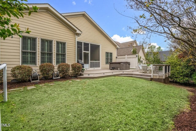 rear view of house with a deck, a lawn, and a hot tub