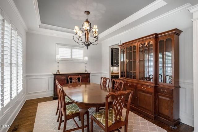 dining space featuring dark wood-style floors, a wainscoted wall, a tray ceiling, a decorative wall, and a chandelier