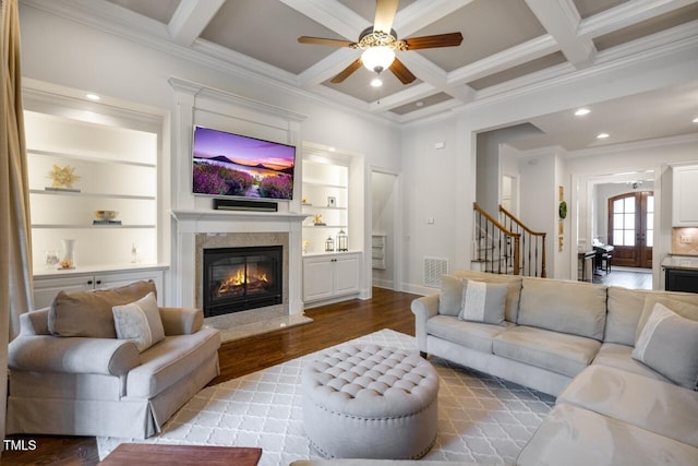 living area with beamed ceiling, coffered ceiling, wood finished floors, a high end fireplace, and stairs