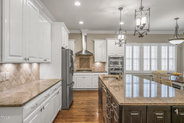 kitchen with a sink, ornamental molding, appliances with stainless steel finishes, wall chimney exhaust hood, and dark wood-style flooring