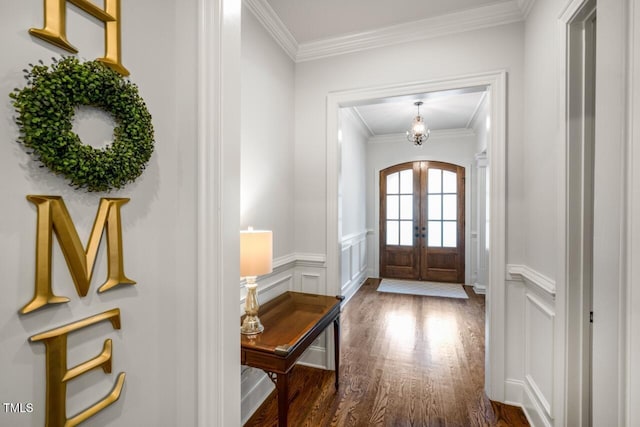 foyer featuring a wainscoted wall, arched walkways, dark wood-style flooring, ornamental molding, and french doors