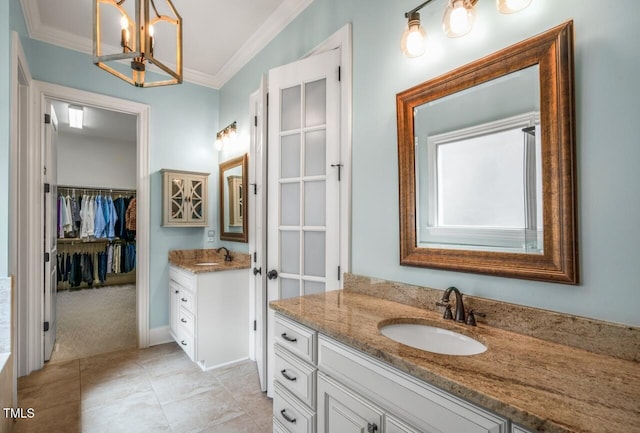 full bath featuring a sink, a walk in closet, two vanities, and crown molding