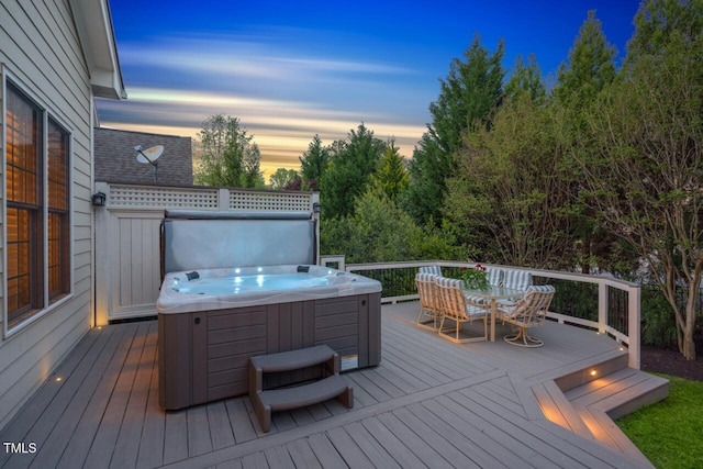 deck at dusk featuring outdoor dining space and a hot tub