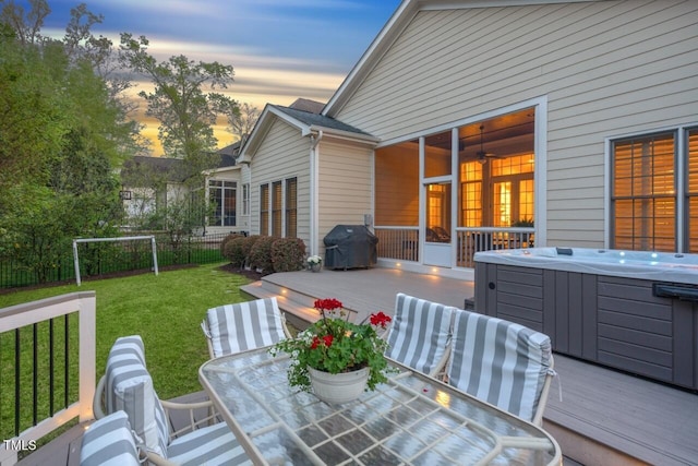 deck with a yard, grilling area, outdoor dining space, and a hot tub