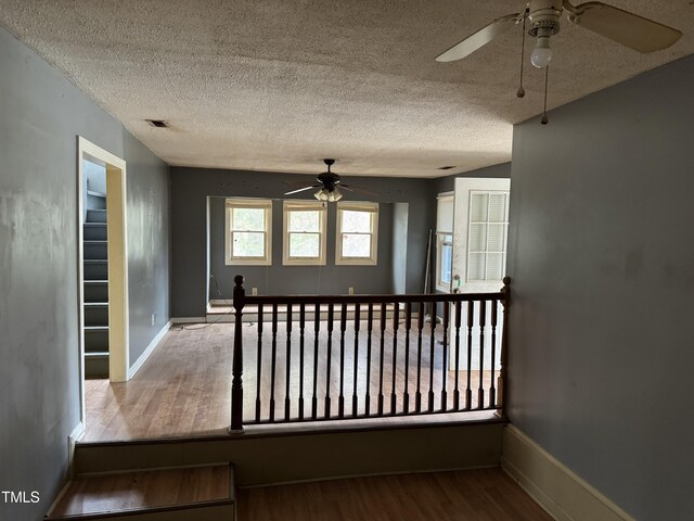 unfurnished room featuring baseboards, a textured ceiling, ceiling fan, and wood finished floors