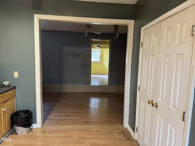 hall with baseboards and light wood finished floors