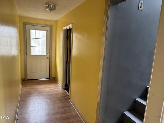 doorway to outside featuring baseboards and light wood-type flooring
