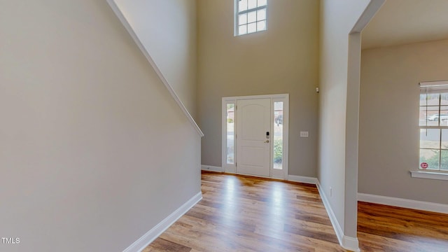 foyer featuring light wood-type flooring, baseboards, and a high ceiling