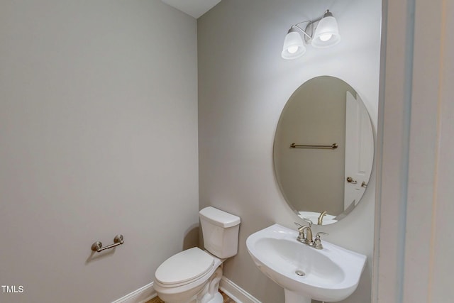 bathroom featuring toilet, baseboards, and a sink