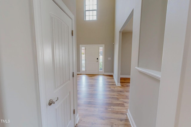 entrance foyer featuring a high ceiling, light wood-style flooring, and baseboards