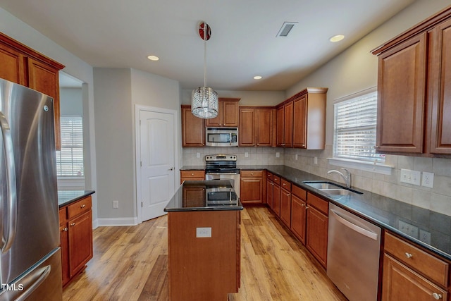 kitchen featuring visible vents, light wood-style flooring, a sink, a kitchen island, and appliances with stainless steel finishes