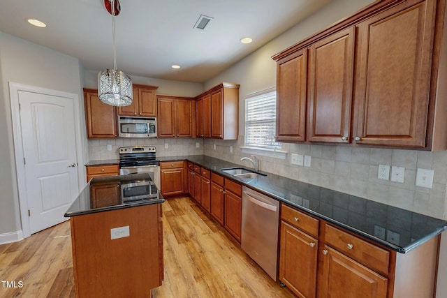 kitchen with a sink, stainless steel appliances, a center island, and light wood finished floors