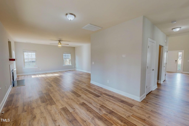 unfurnished room with visible vents, light wood-style flooring, a fireplace, and baseboards