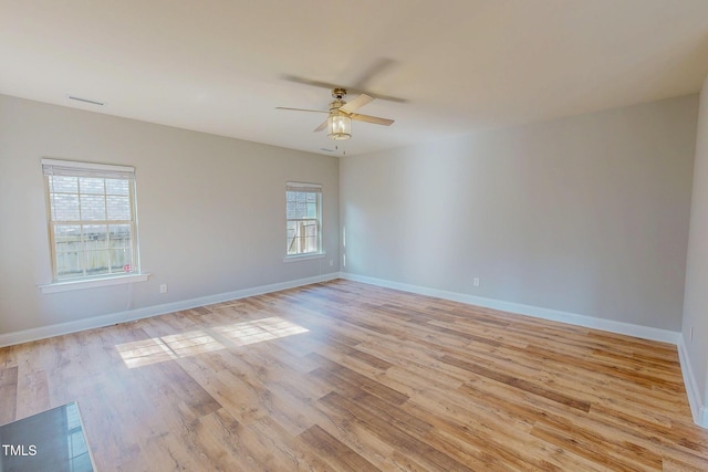 spare room featuring a ceiling fan, plenty of natural light, baseboards, and light wood-type flooring