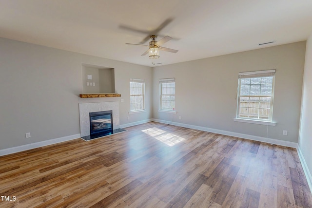 unfurnished living room featuring wood finished floors, a wealth of natural light, and a tile fireplace